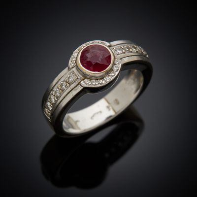 a close up of a ring with a ruby stone and diamonds