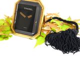 a gold frame with a black watch and a black tassel