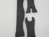 two pieces of black plastic sit next to each other on a white surface