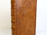 un vieux livre à la couverture marron posé sur une table blanche