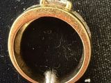 a gold ring with a diamond in it on a black surface