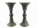 two metal vases sitting next to each other on a white surface
