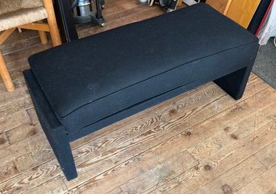 a black bench sitting on a wooden floor in a room