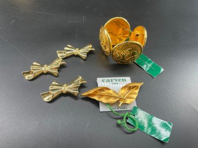Plusieurs pièces d'or sont posées sur une table, accompagnées d'étiquettes et d'étiquettes