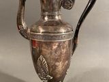 silver plated coffee pot with a black handle on a metal stand