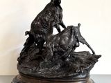 une statue en bronze représentant une chèvre et une chèvre perchée sur un rocher