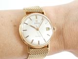 a gold watch on a woman ' s wrist with a white dial