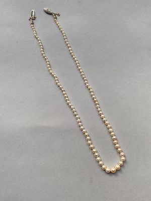 un collier de perles blanches avec un fermoir en or sur fond blanc