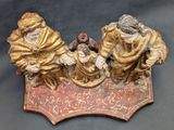 a figurine of three people sitting on a bench