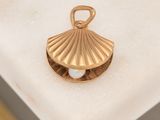 a gold shell with a pearl in it on a marble surface