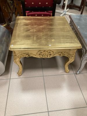 une table basse dorée et deux chaises dans une pièce