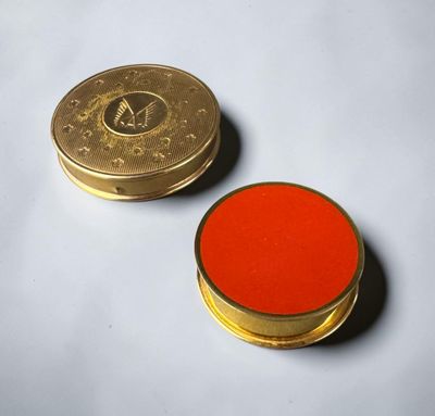 a gold coin and a red button on a white surface