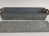 two metal trays with handles and handles on a white surface