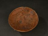 a brown bowl on a black surface with a black background