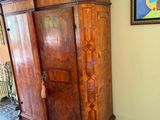 a wooden armoire in a room with a painting on the wall