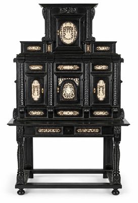 un meuble ancien peint en noir et or, surmonté d'une horloge