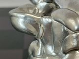 a silver statue of a person holding a cell phone