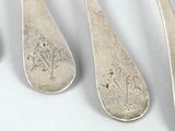 four silver spoons with designs on them sitting next to each other