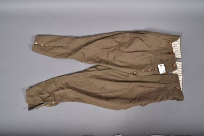 un pantalon marron muni de boutons, posé sur une surface blanche