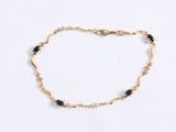 a close up of a gold bracelet with black beads on a white background