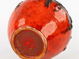 a red vase with a hole in it on a white surface