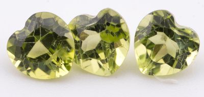 une paire de perles en cristal vert en forme de cœur sur un fond blanc