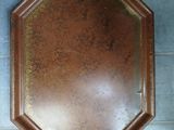 a brown plate that is on the wall next to a vase