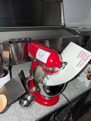 a red mixer sitting on a counter next to other kitchen utensils