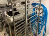 une étagère métallique sur laquelle sont posés plusieurs plateaux, dans une cuisine