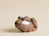 une petite figurine représentant une grenouille posée sur une table