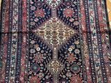 un tapis persan antique sur un plancher en bois