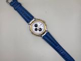gros plan d'une montre sur une surface blanche avec un bracelet bleu