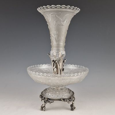 un vase en argent posé sur un socle, sur un fond gris