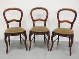 trois chaises en bois aux assises rembourrées vertes, adossées à un mur blanc