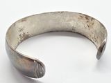 a close up of a silver bracelet on a white surface