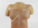 a clay sculpture of a woman ' s torso on a white surface