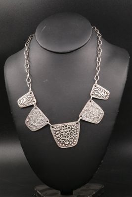 un collier en argent présenté sur un mannequin, sur fond noir