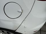 the rear end of a white car with a hole in it