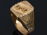 a close up of a gold signet ring on a black surface