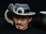 a mug with a cowboy hat on it next to a mug with a mustache
