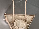 a small metal object hanging from a chain on a black cloth