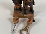 a figurine of two men standing next to a bottle opener