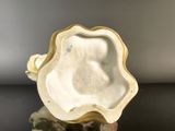 a close up of a white and gold vase on a table