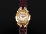 un gros plan d'une montre en or sertie de diamants, montée sur un bracelet rouge