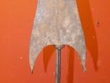 a metal object that is on a stand in front of an orange wall