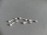 two pairs of silver nose piercings on a gray surface
