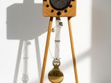 a wooden clock on a stand with a bell on top of it