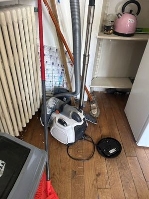 a vacuum and a broom in a room with a radiator