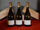 three bottles of wine sit on a red cloth next to a wooden box
