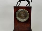 statue d'un cheval posée sur un socle en bois, surmontée d'une horloge